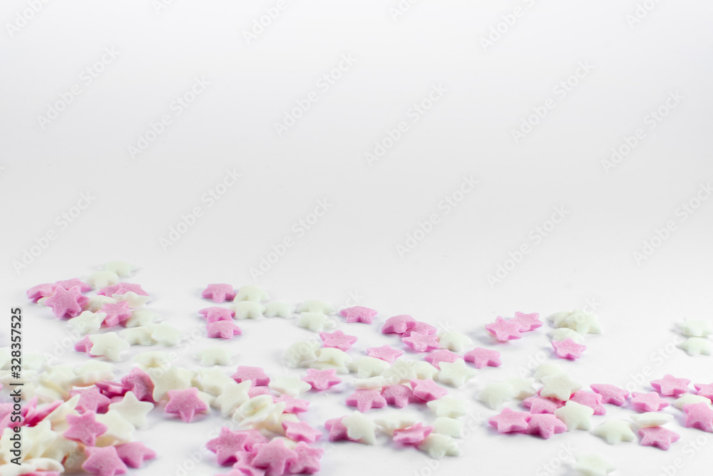 Fototapeta premium Sugar star cake decorations pink and white, little decors for muffins, gingerbread, cookies and all other baking. White background bright colours with copy space.