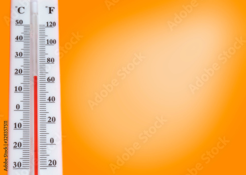 White thermometer with scale on orange background