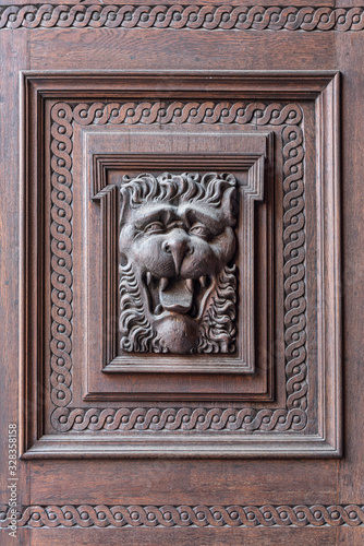 Lion head carved on wood door. Bas-relief of a lion on a door