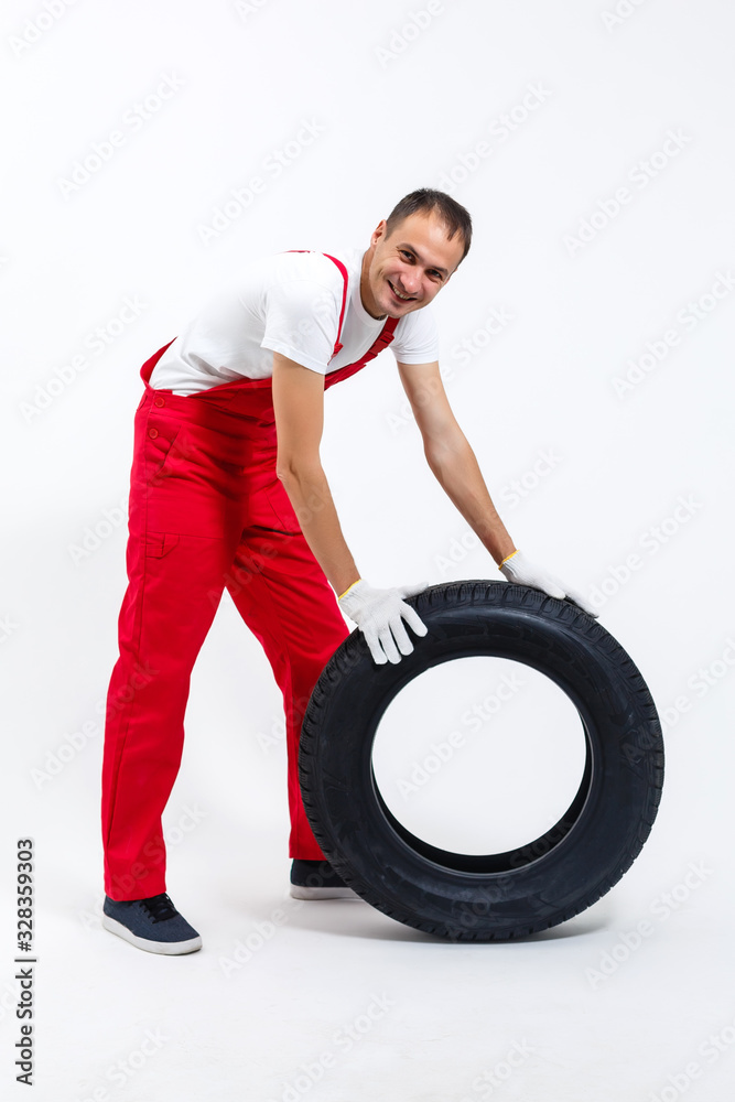 Mechanic holding a tire tire at the repair garage. replacement of winter and summer tires. Mechanic holding a tire tire at the repair garage. replacement of winter and summer tires.