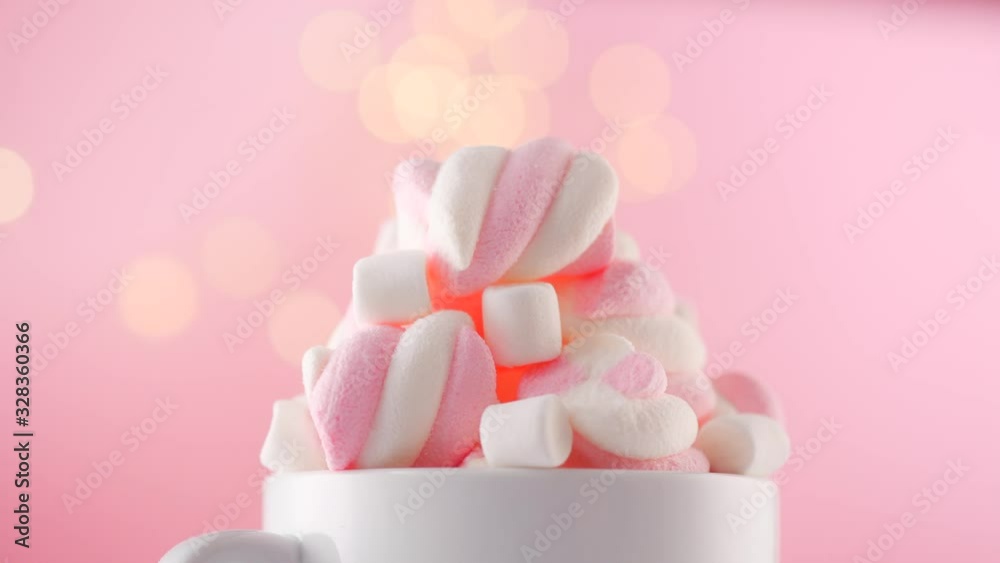 Marshmallow. Close-up of Marshmallows colorful chewy candy, over pink bokeh background, closeup. Sweet holiday food dessert in a cup with hot chocolate close-up. Candies rotate. 4K UHD video Marshmallow. Close-up of Marshmallows colorful chewy candy, over pink bokeh background, closeup. Sweet holiday food dessert in a cup with hot chocolate close-up. Candies rotate. 4K UHD video