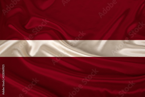 photo of the national flag of Latvia on a luxurious texture of satin, silk with waves, folds and highlights, close-up, copy space, concept of travel, economy and state policy, illustration