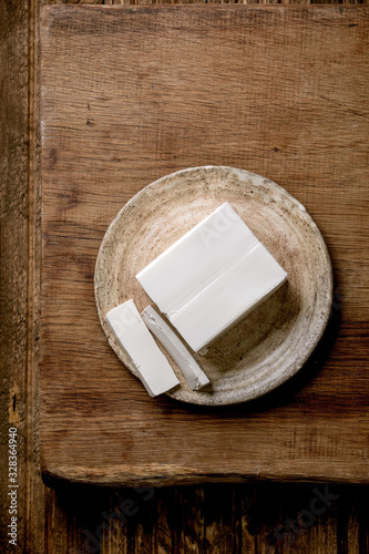 Silk tofu japanese soy cheese whole piece on ceramic plate with chopsticks over wooden table. Flat lay, space