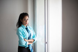 Indian Bengali attractive brunette young woman in office wear standing in front of a window in a corporate office/bpo/call center. Indian corporate lifestyle.