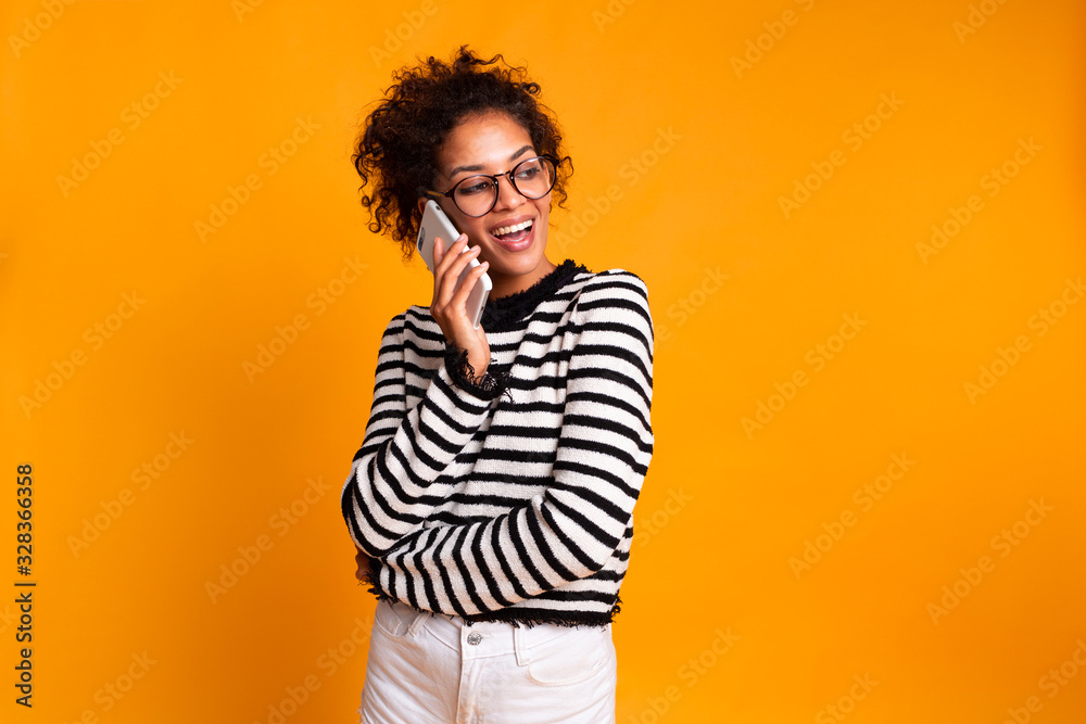 Portrait of cute joyful woman with trendy hairstyle wearing basic t-shirt talking on mobile phone isolated over yellow background Portrait of cute joyful woman with trendy hairstyle wearing basic t-shirt talking on mobile phone isolated over yellow background