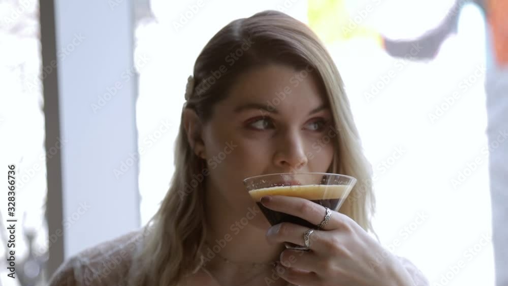 woman sitting in a cafe enjoying a chocolate coffee martini during mid day. she is happy drinking the alcoholic beverage in comfort while wearing fashionable elegant clothing woman sitting in a cafe enjoying a chocolate coffee martini during mid day. she is happy drinking the alcoholic beverage in comfort while wearing fashionable elegant clothing