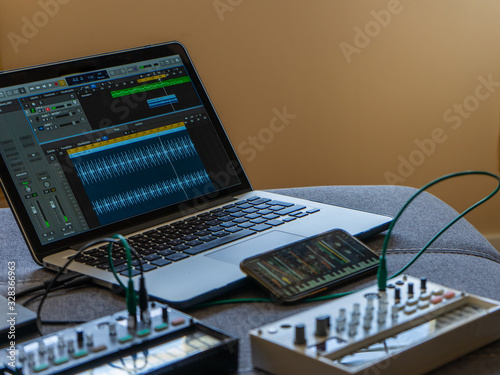 Close up view of fm synthesizer, sampler, smartphone with modular synthesizer and laptop with open audio editor Electronic music concept. photo