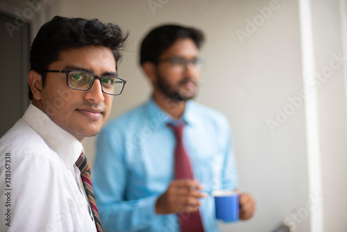 Corporate meetings with coffee/tea between young and energetic Indian Bengali bosses/officers/managers and secretary at balcony of the office building regarding a project. Indian corporate lifestyle