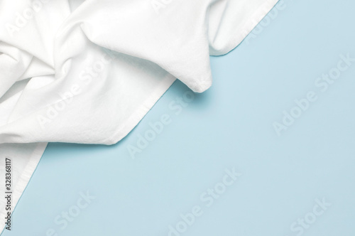 White crumpled natural cotton fabric on delicate blue background top view flat lay with copy space. Natural linen background. Eco textiles. White Fabric texture. Fabric backdrop