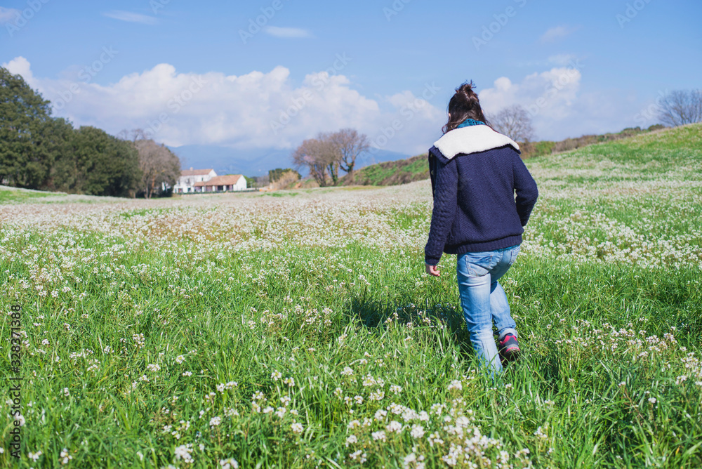 Rear view of hispanic brunette woman in casual wear walking on field