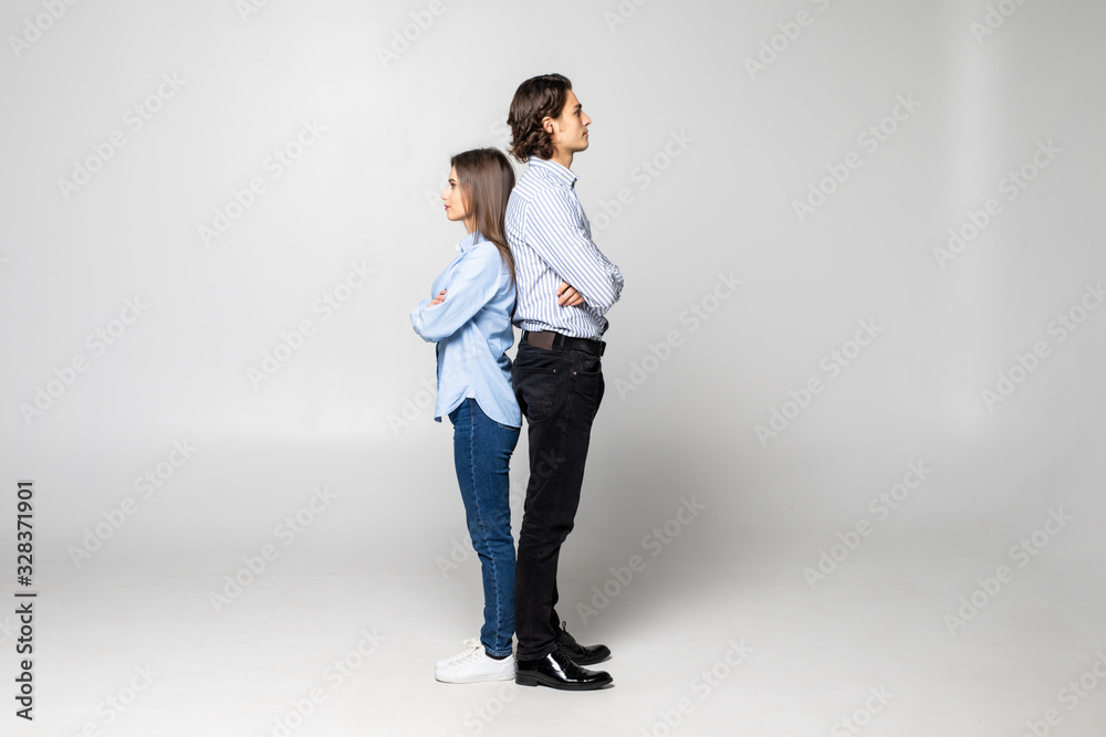 Lovely young couple sitting back to back isolated on white background Lovely young couple sitting back to back isolated on white background