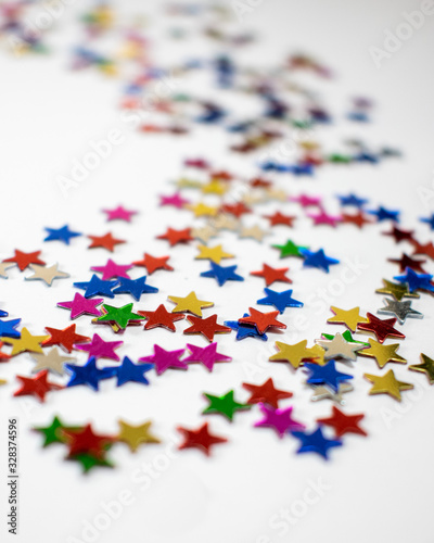 Confetti stars on white background, festive colorful and shiny stars on white background with copy space.