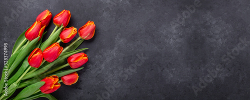 Greeting Card for Mother's or Women's Day. Bouquet of red tulips on a dark stone table. Spring background. Top view. Copy space