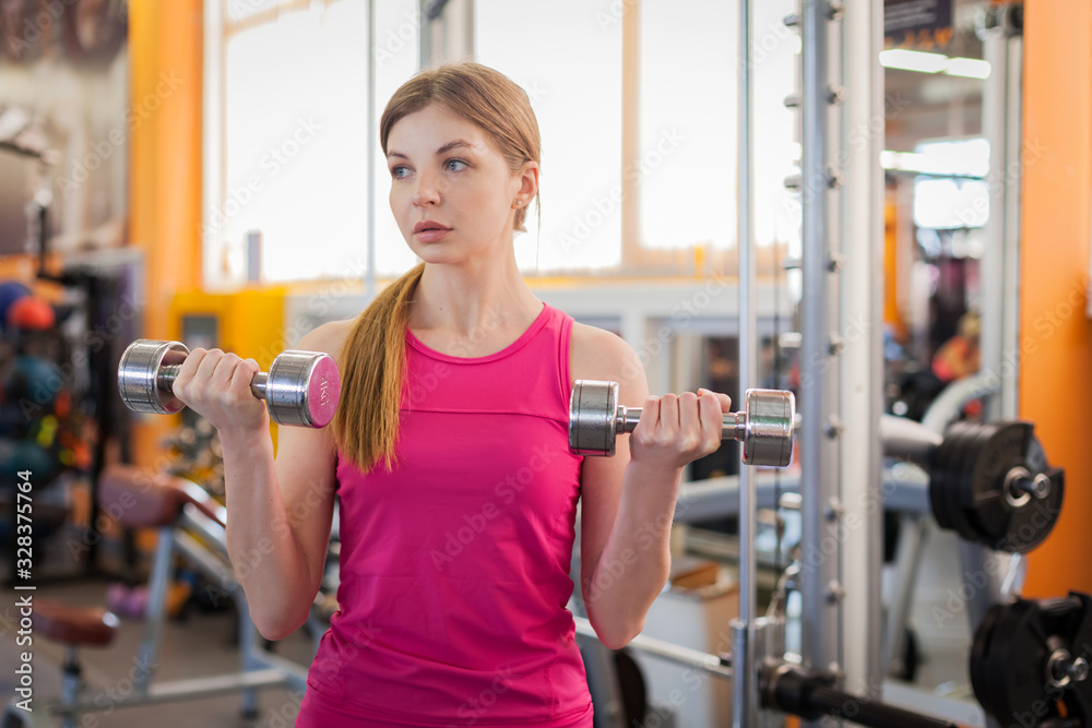 Active woman lifting dumbbells in the gym Active woman lifting dumbbells in the gym