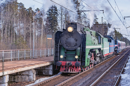 Retro steam train departs from the railway station platform.