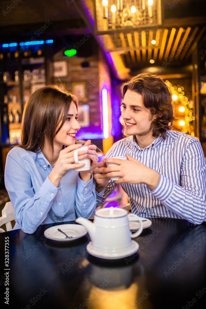 Portrait of affectionate young couple in stylish clothes having coffee in cafe