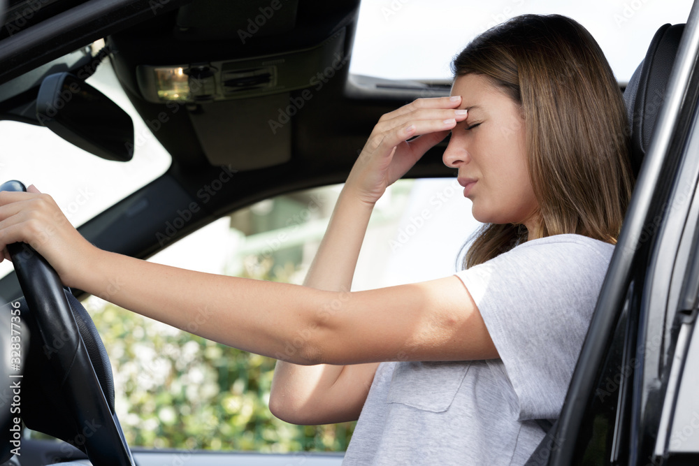 young female driver with headache in a car
