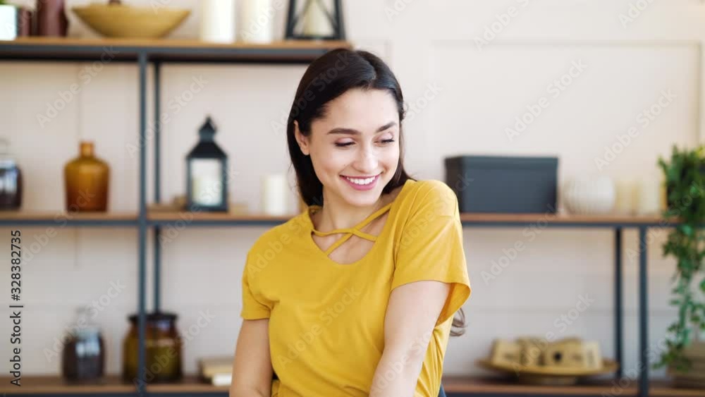 Pleased girl sitting in living room and smiling at camera Pleased girl sitting in living room and smiling at camera