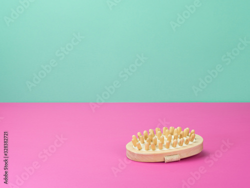 Massage brush, bathroom accessories on pink and turquoise background.