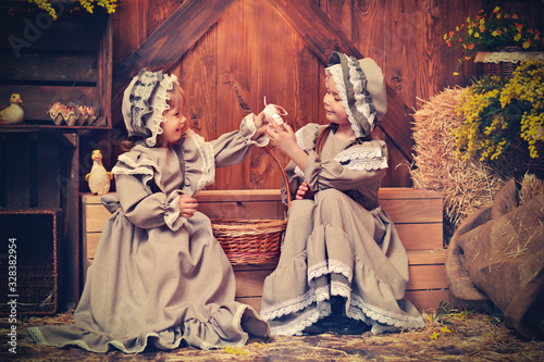 Happy easter! cute twins girls sisters dressed as rabbits with eggs on wooden background