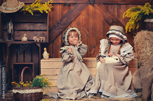 Little girls in retro outfits play with an easter bunny. Country style.Art photo.