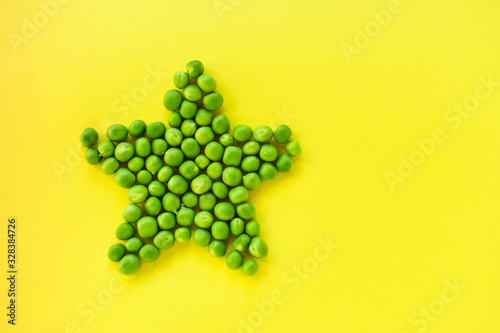 Star laid out of green peas on a yellow background. The concept of proper nutrition.