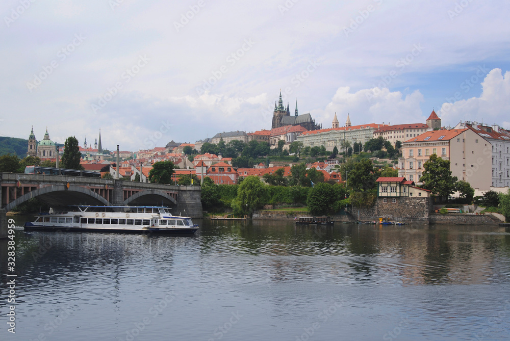 Landscape of Prague, Czech Republic on a sunny day. View of St. Vitus Cathedral. In the foreground is a boat on the Vltava river .