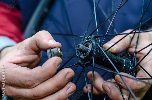 Bicycle repair in the workshop by a professional mechanic. Bulkhead hub front wheel. Replacing grease and washing bearings. Cone in hand closeup. photo