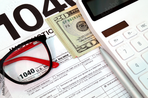 Income tax form with with instruction, money, calculator and glasses