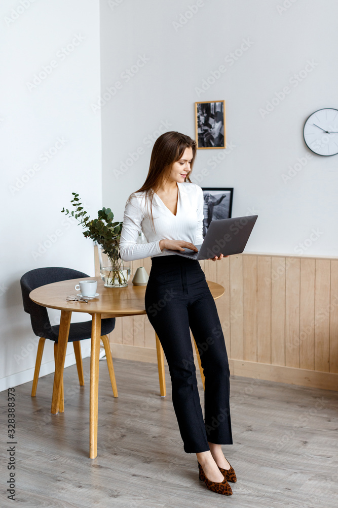 A young business woman stands in a room, holds a laptop and solves problems. Business woman concept A young business woman stands in a room, holds a laptop and solves problems. Business woman concept