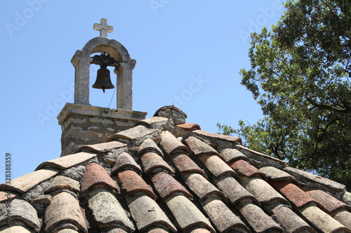 old church tower with a clock on a roof with multicolored roofing