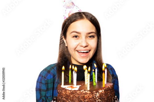 A young Russian girl celebrates her eighteenth birthday. Birthday girl of 18 years with a cake smiles and looks into the frame on a white background.