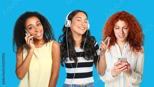 Different young women using mobile phones on color background