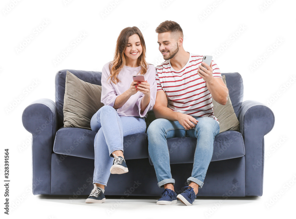 Young couple with mobile phones sitting on sofa against white background Young couple with mobile phones sitting on sofa against white background