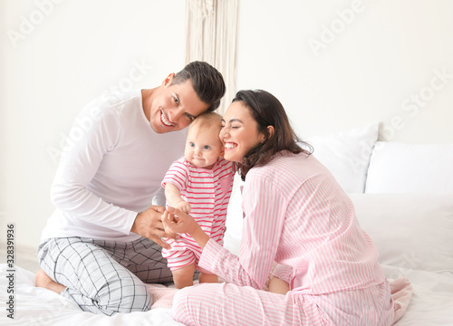 Cute baby with parents in bedroom