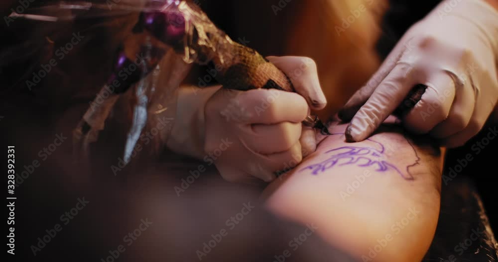Tattoo artist making a tattoo of a deer on a person's hand. Close up, slow motion, shallow depth of field. BMPCC 4K