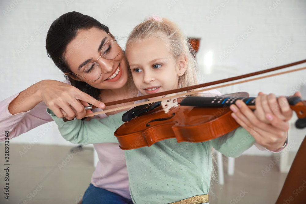 Private music teacher giving violin lessons to little girl at home Private music teacher giving violin lessons to little girl at home