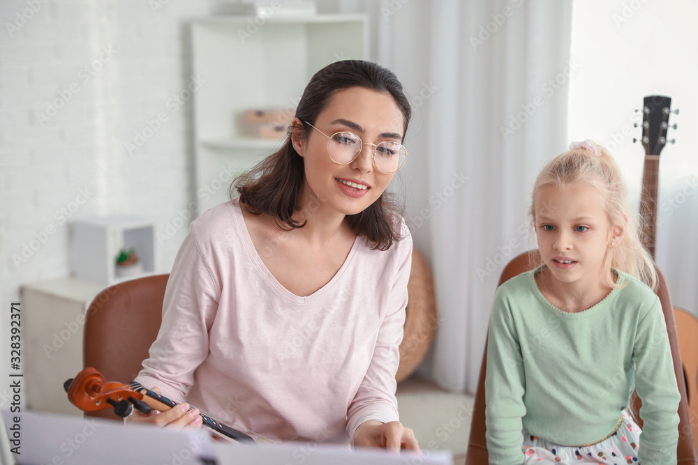 Private music teacher giving violin lessons to little girl at home Private music teacher giving violin lessons to little girl at home