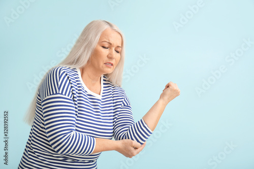Senior woman suffering from Parkinson syndrome on color background