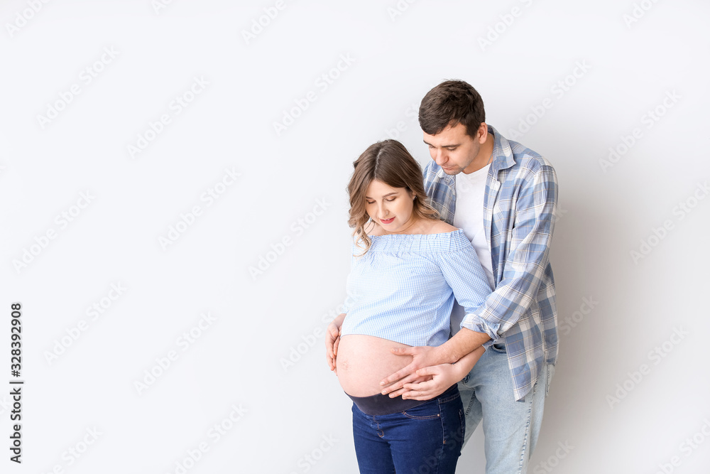 Beautiful pregnant couple on grey background