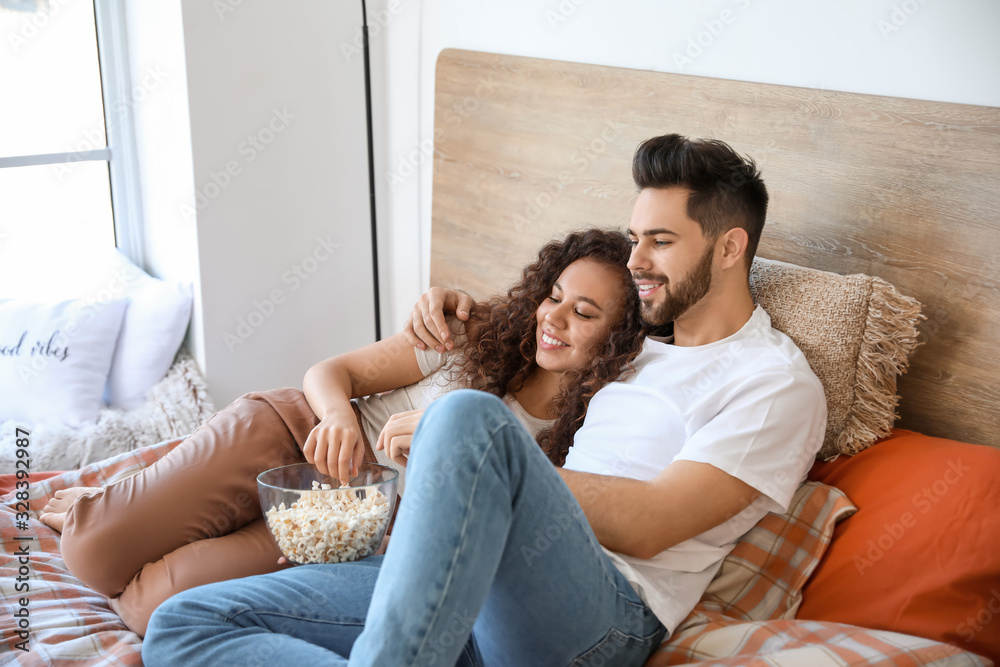 Happy young couple watching movie in bedroom Happy young couple watching movie in bedroom