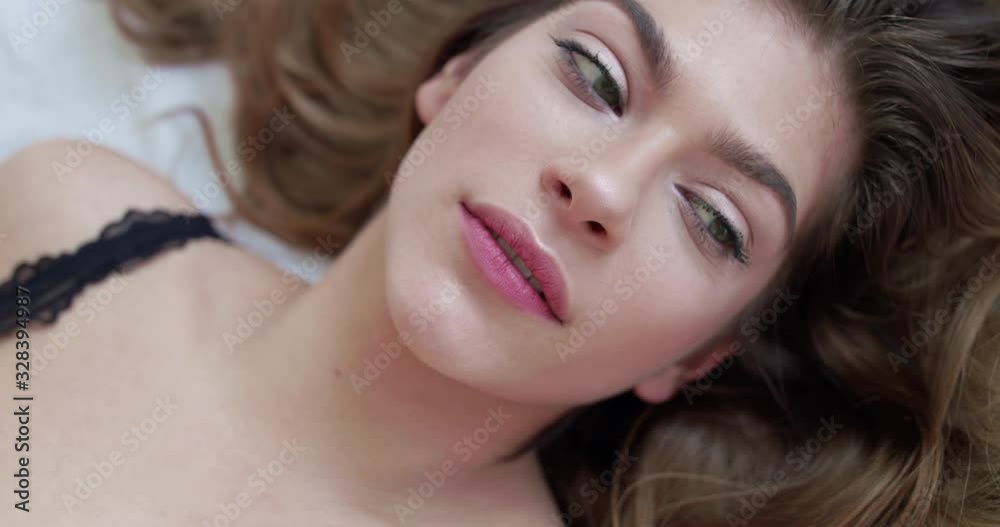 Macro portrait of attractive woman lying on bed and looking up at camera Macro portrait of attractive woman lying on bed and looking up at camera