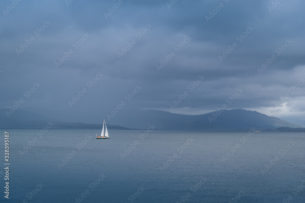 Sailing yacht at Hebrides islands in cloudy weather. Island of Mull, Scotland.