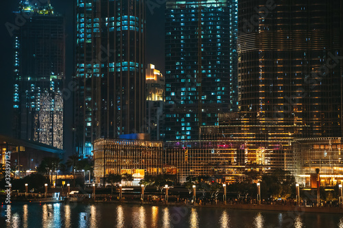 Dubai downtown buildings night scene with reflection in water, UAE, luxurious travel and tourism.