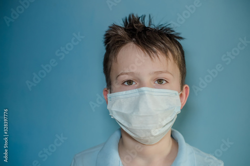 boy in medical mask on blue background. child with flu, influenza or cold protected from viruses, pollution in bad epidemic situation, among patients with coronavirus © Maryna