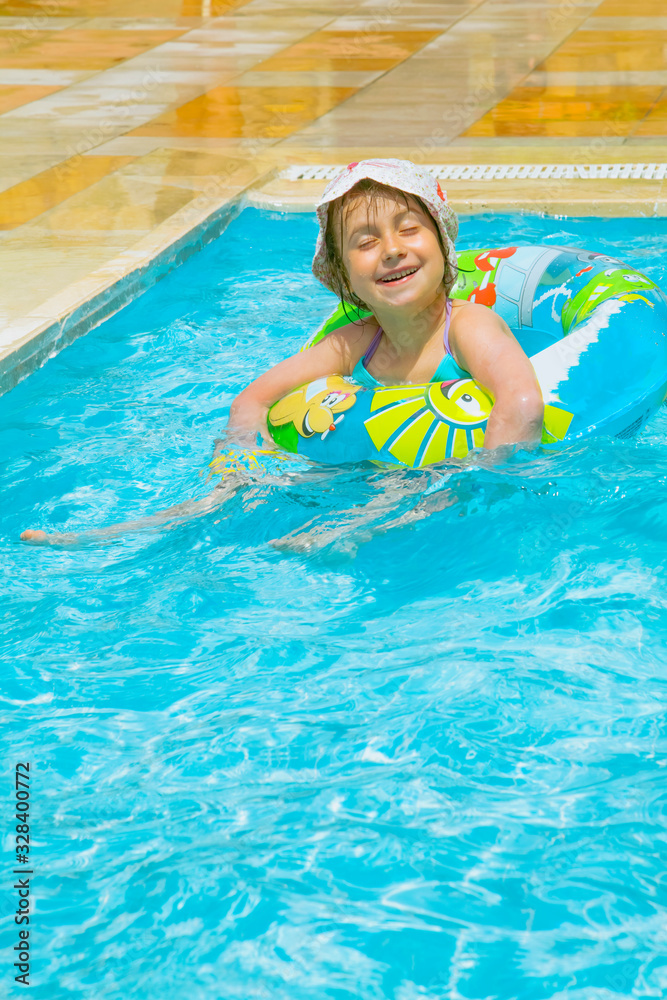 Funny portrait of happy cute little child girl in swimming pool. Summer holiday.