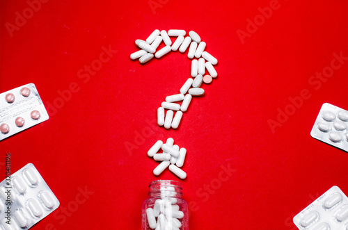 Question mark from white tablets on a red background. The medical concept with copy space © Artur Falgowski