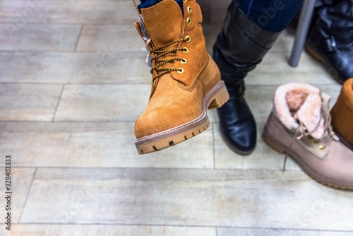 Woman wearing shoe in clothing boutique . Yellow shoe on foot