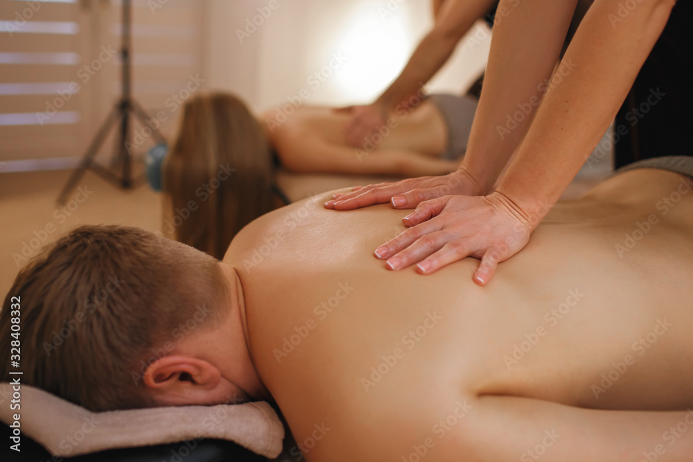 Fototapeta premium Man and woman relax in the spa, professional masseurs make massage, family vacations in the spa