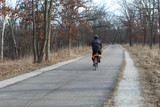 Man riding a bicycle on the North Branch Trail in early spring at Miami Woods in Morton Grove, Illinois